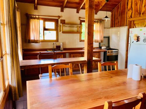 a kitchen with a wooden table and a refrigerator at Fly Fishing Cabin, Great Views in Junín de los Andes