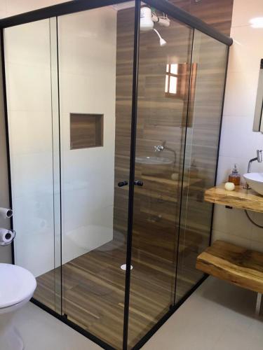 a shower with a glass door in a bathroom at Chalé Sonho Diniz 1 in Monte Verde