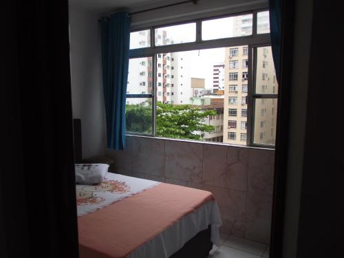 a bedroom with a bed and a large window at Apartamento Temporada in São Vicente