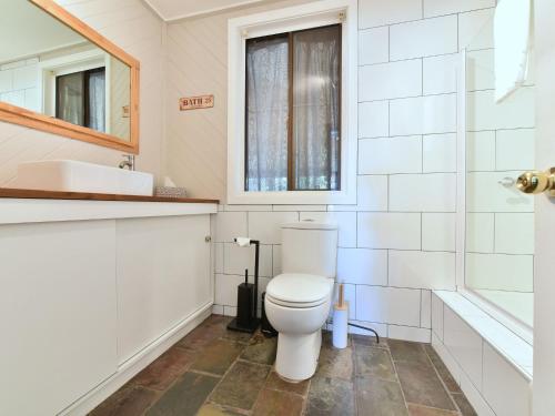 a white bathroom with a toilet and a sink at Soldiers Cottage picturebook vineyard home in Bulga