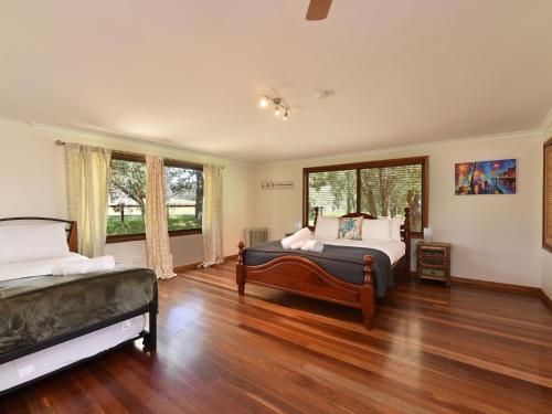 a bedroom with two beds and a large window at Soldiers Cottage picturebook vineyard home in Bulga