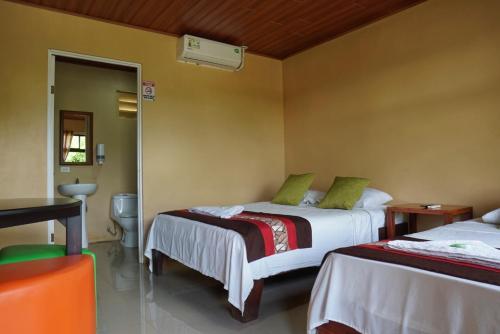 a hotel room with two beds and a mirror at Hotel Heliconia Los Chiles in Los Chiles