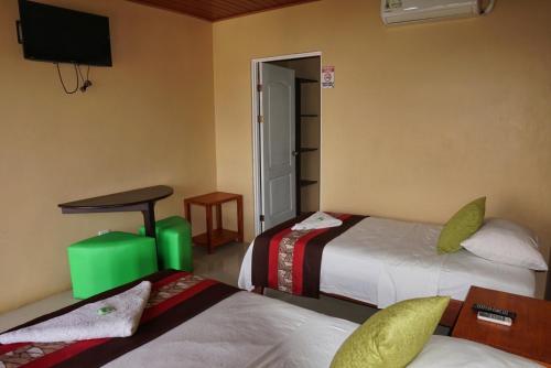 a bedroom with two beds and a tv on the wall at Hotel Heliconia Los Chiles in Los Chiles