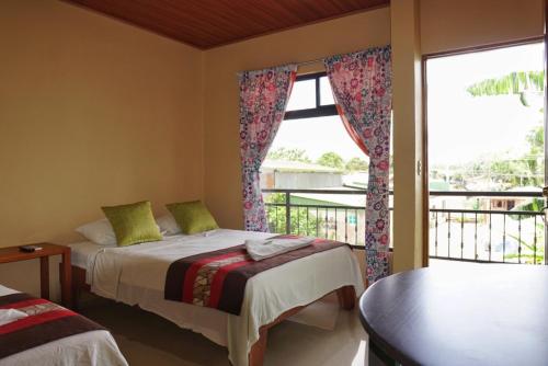 a bedroom with two beds and a balcony at Hotel Heliconia Los Chiles in Los Chiles