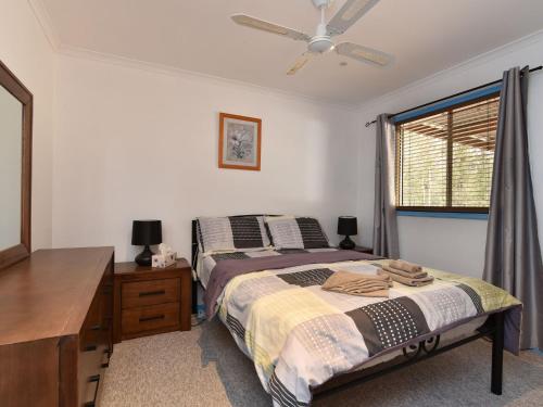 a bedroom with a bed and a dresser and a window at Wallaby Cottage in Ellalong