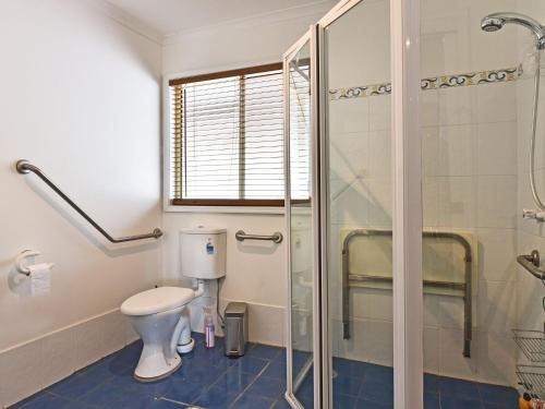 a bathroom with a toilet and a glass shower at Wallaby Cottage in Ellalong