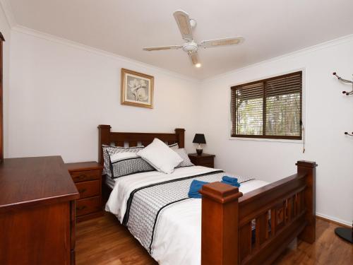 a bedroom with a bed and a ceiling fan at Australiana Cottages in Ellalong