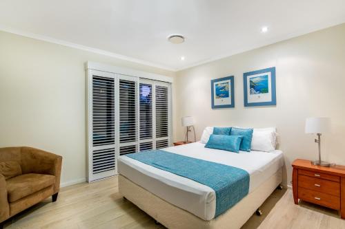 a bedroom with a bed and a chair and a window at The Village Holiday Apartments at Burleigh Heads in Gold Coast