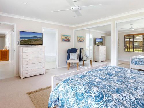 a bedroom with a blue and white bed and a tv at Beach House in Hawks Nest
