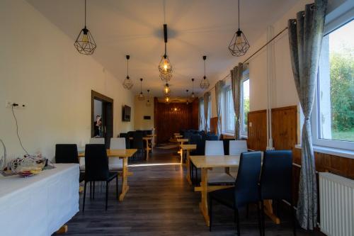 a dining room with tables and chairs and windows at Villa Zarra in Habovka