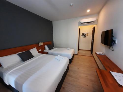 a hotel room with two beds and a television at Hotin Inn in Kuching