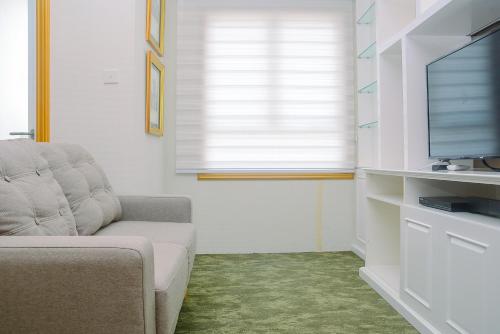 a living room with a couch and a flat screen tv at Modern Studio at Titanium Square Apartment By Travelio in Jakarta