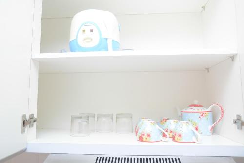 a white cupboard with cups and a toy in it at Modern Studio at Titanium Square Apartment By Travelio in Jakarta