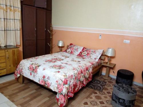 1 dormitorio con 1 cama con colcha de flores y 2 lámparas en Appartement ABS, en Abiyán