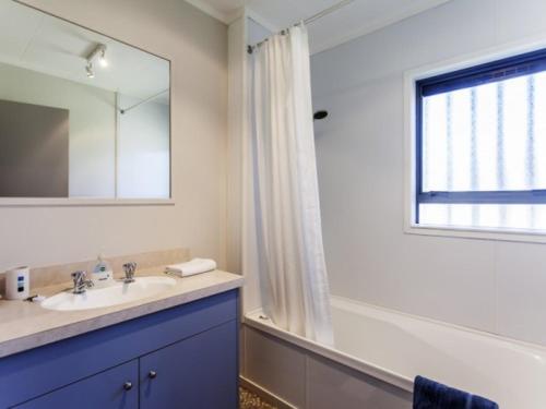 uma casa de banho com um lavatório, um espelho e uma janela em Hahei Beach House - 3 Bedroom em Hahei