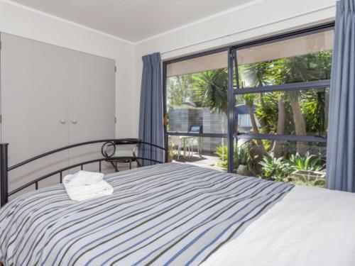 a bedroom with a bed and a large window at Hahei Beach House - 3 Bedroom in Hahei