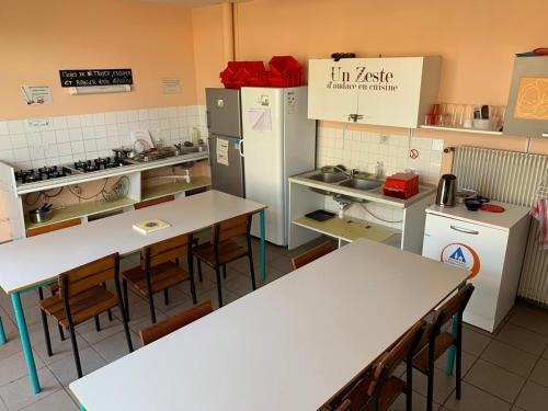 eine Küche mit Tischen und Kühlschrank in einem Restaurant in der Unterkunft Auberge de Jeunesse HI Belle-Île-en-Mer in Le Palais
