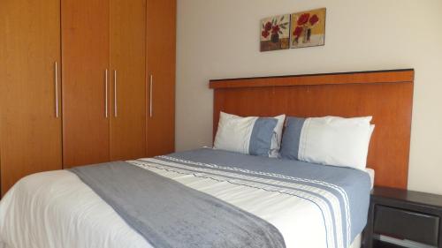 a bedroom with a bed with a wooden headboard at B.R.O.Homes and Villas in Port Elizabeth
