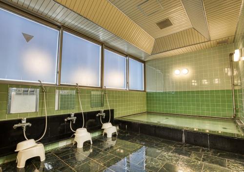 a bathroom with three urinals and a bath tub at APA Hotel Marugame Ekimaeodori in Marugame