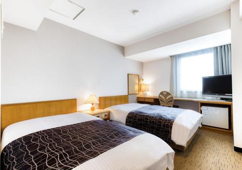a hotel room with two beds and a flat screen tv at APA Hotel Marugame Ekimaeodori in Marugame