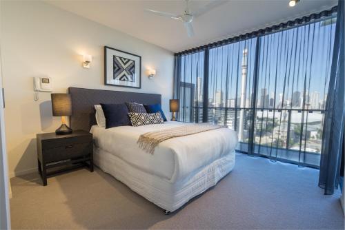 a bedroom with a large bed and a large window at Arena Apartments by CLLIX in Brisbane