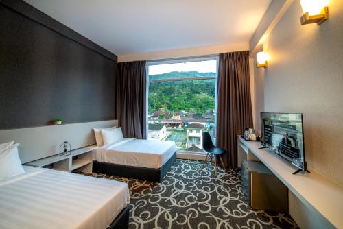 a hotel room with two beds and a television at Deview Hotel Penang in Ayer Itam