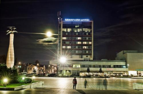 a person standing in front of a building at night at Mercure Marijampole in Marijampolė