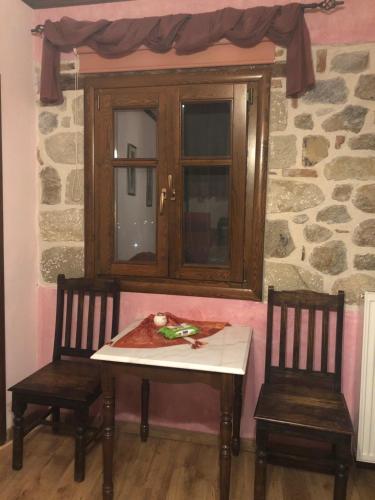 a table and two chairs in a room with a window at Archontiko Mesohori Meteora in Kalabaka