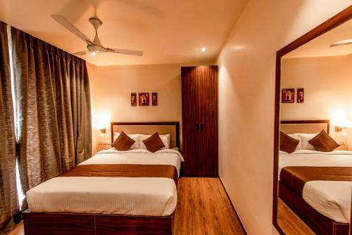 a hotel room with two beds and a mirror at The Green Boutique in Panaji