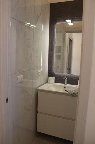 a white bathroom with a sink and a mirror at Appartamento Albachiara Vistamare in Cesenatico