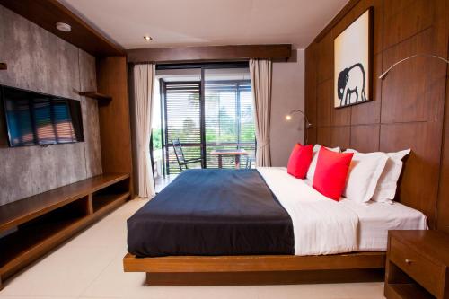1 dormitorio con 1 cama grande con almohadas rojas en Amenity Apartel Samui, en Lamai