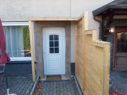 a wooden shed with a door and a fence at Ferienwohnung Linde Otzenhausen in Nonnweiler