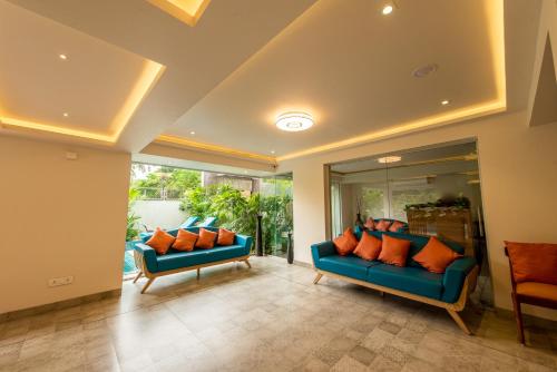 a living room with two blue couches and orange pillows at The Green Boutique in Panaji