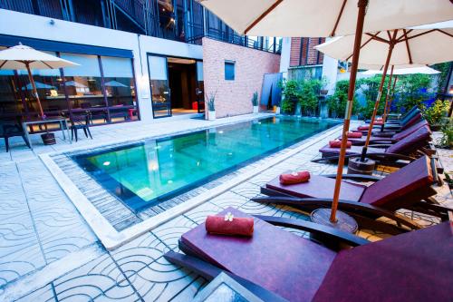 a pool with chairs and umbrellas next to a building at Amenity Apartel Samui in Lamai