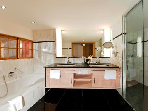 a bathroom with a sink and a tub and a mirror at Wellnesshotel Schönruh - Adults only in Seefeld in Tirol