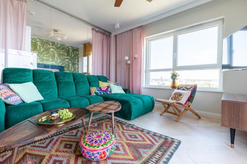 ein Wohnzimmer mit einem grünen Sofa und einem Tisch in der Unterkunft Apartamenty Your Seaside in Danzig