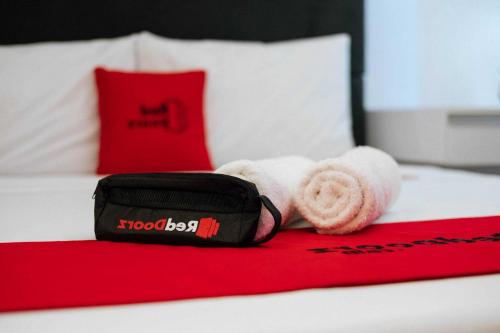 a red and white bed with a black bag and towels at RedDoorz Syariah @ Sunan Bonang Magelang in Magelang