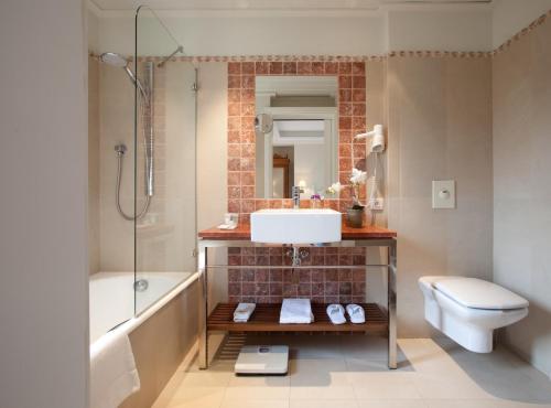 a bathroom with a sink and a tub and a toilet at Hotel MR Les Rotes in Denia