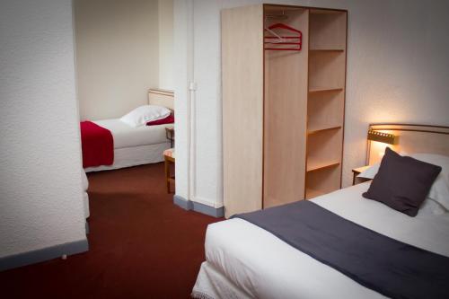 ein Hotelzimmer mit 2 Betten und einem Schrank in der Unterkunft Le Terminus in Tarascon