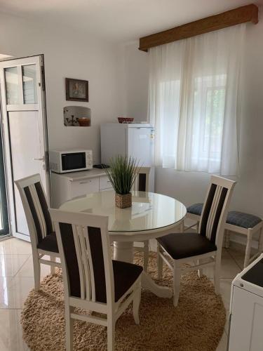 a kitchen with a white table and chairs and a white table and chairs at Apartments Vuk in Lustica