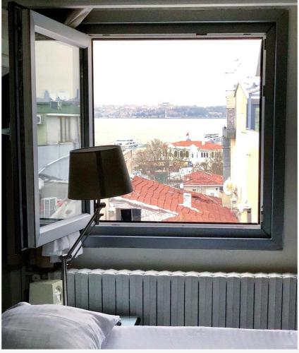 a bedroom with a large window with a bed and a lamp at My Kent Hotel in Istanbul