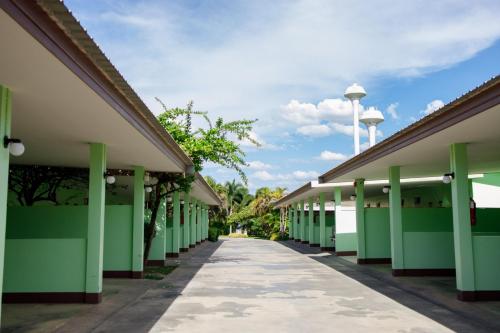 a row of green buildings with a pathway at S Hotel Kanchanaburi in Kanchanaburi