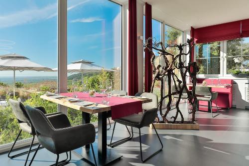 a dining room with a table and chairs and windows at Arens Hotel 327mNN in Sankt Martin