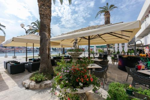 a patio with tables and chairs and umbrellas at Hotel Concordia in Trogir