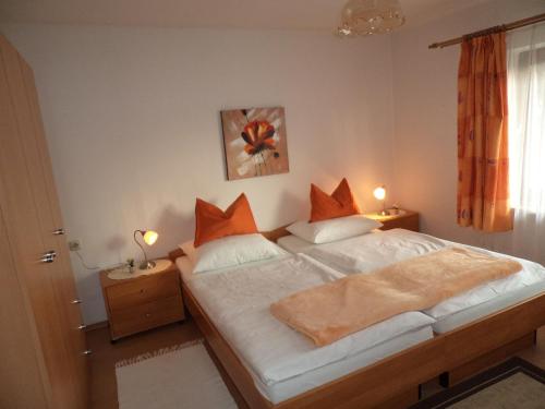 a bedroom with a bed with orange pillows and two lamps at Gästehaus Verena in Mondsee