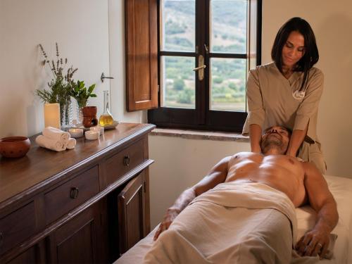 a woman giving a man a massage in a bed at Relais Villa Monte Solare Wellness & SPA in Panicale