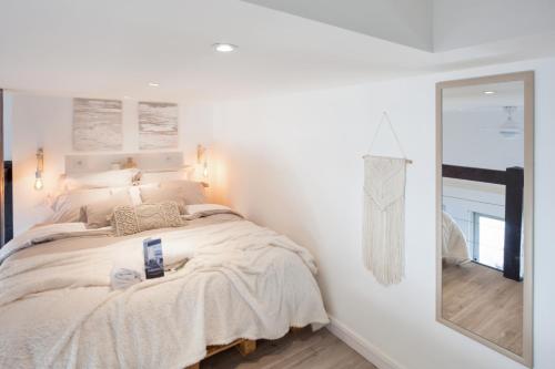 une chambre blanche avec un lit et un miroir dans l'établissement Duplex Sinèpe - Welkeys, à Trouville-sur-Mer