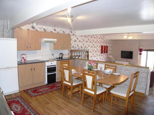a kitchen and dining room with a table and chairs at Cae Berllan Cottages in Groeslon