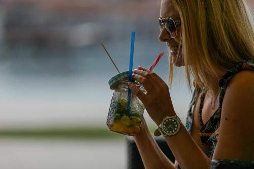 a woman wearing sunglasses is holding a drink at Hotel Concordia in Trogir