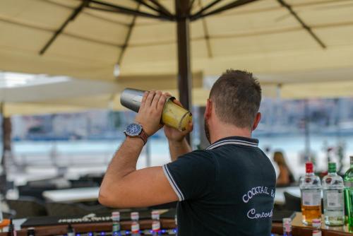a man drinking from a bottle in a bar at Hotel Concordia in Trogir